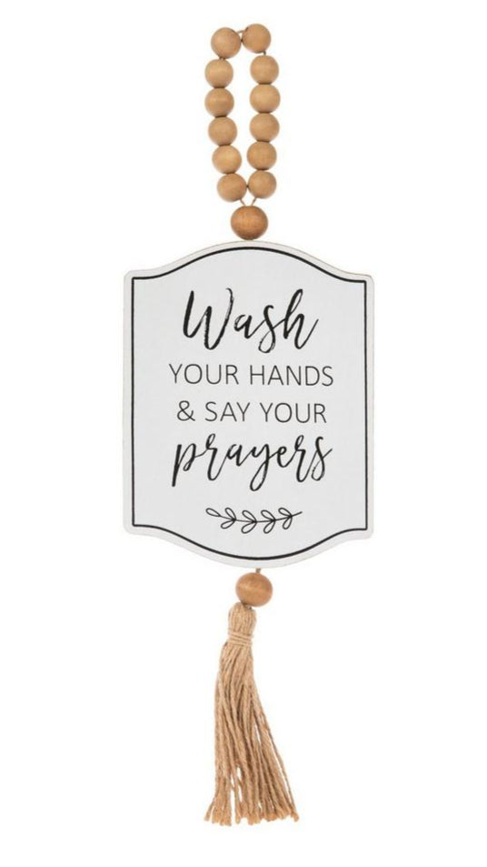 Decorative hanging sign with text 'Wash your hands & say your prayers' on a white background